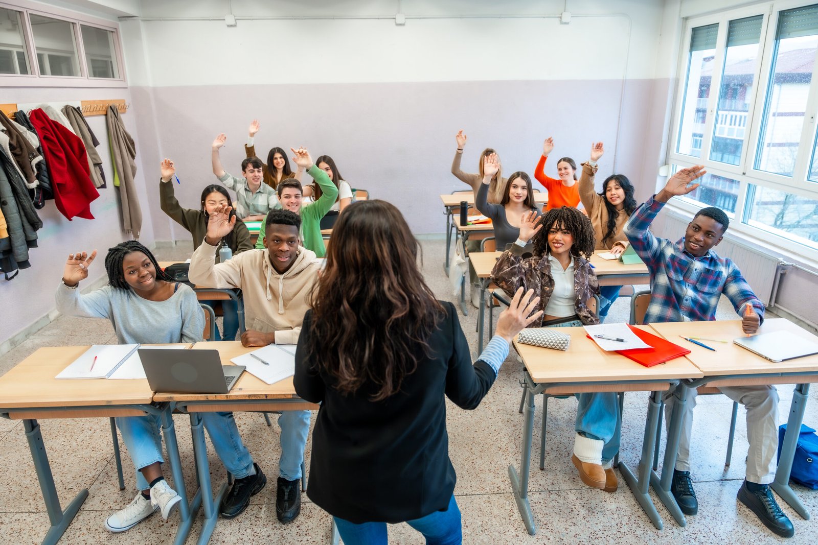University students raising hands in classroom during lesson Multi ethnic university students enthusiastically raising hands to respond to the teacher's questions during an engaging classroom lesson
